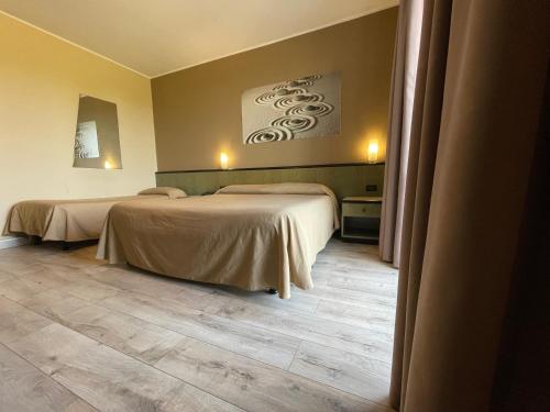 a bedroom with two beds and a wooden floor at Lo Scoiattolo in Massino Visconti