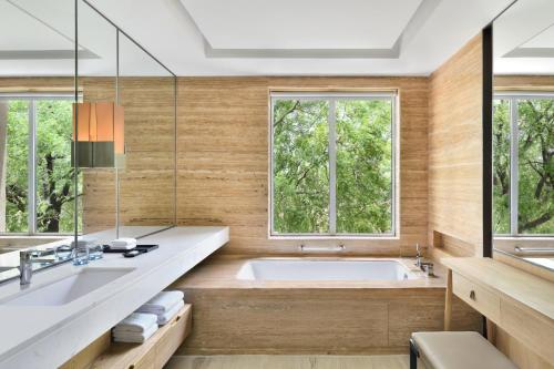 a bathroom with a tub and two windows at Courtyard by Marriott Aravali Resort in Faridabad