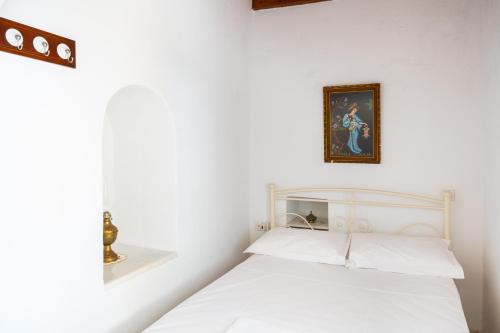 a bedroom with a white bed with a picture on the wall at Zeus House in Philotium