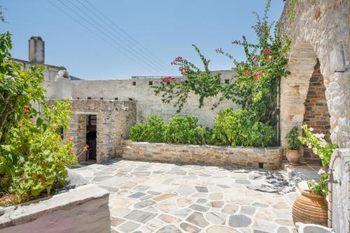 a stone courtyard with plants and a brick wall at Zeus House in Philotium