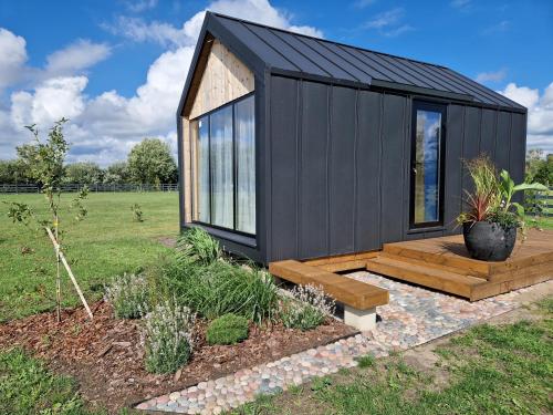 una pequeña casa negra con terraza de madera en Rita Sapnis, en Nida