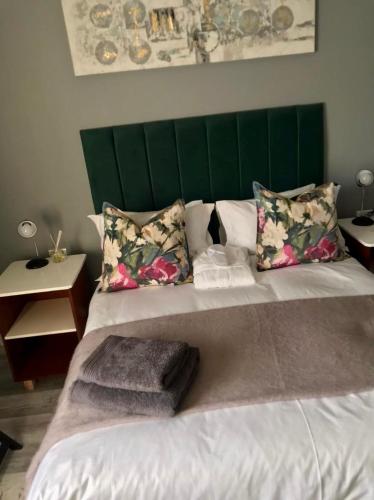 a large bed with a green headboard and pillows at Recoupe in East London