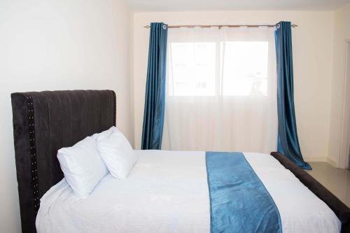 埃爾多雷特的住宿－Staycation with les，一间卧室配有一张带蓝色窗帘的床和一扇窗户