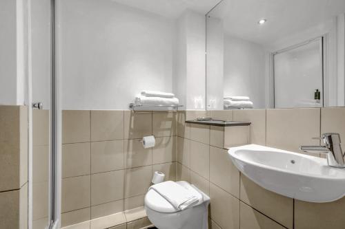 a bathroom with a sink and a toilet and a mirror at Roomzzz Leeds City West in Leeds