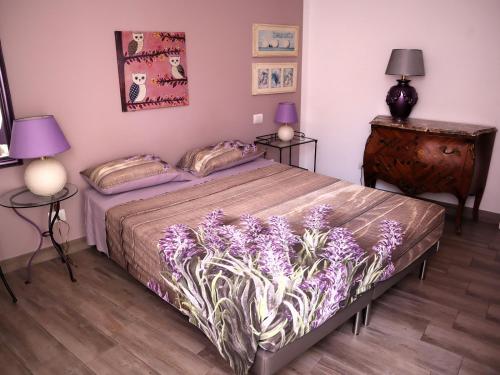 a bedroom with a bed with purple flowers on it at Ventitrémarzo Guest House in Novara