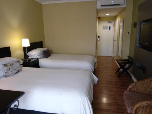 a hotel room with two beds and a couch at Protea Hotel by Marriott Bloemfontein in Bloemfontein