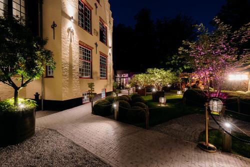 a courtyard of a building with chairs and trees at night at Boutiquehotel 't Fraeyhuis - adults only in Bruges