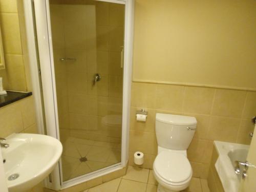 a bathroom with a shower and a toilet and a sink at Protea Hotel by Marriott Bloemfontein in Bloemfontein