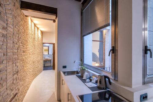 a bathroom with a sink and a brick wall at C&O Savoia Deluxe Rooms in Cagliari