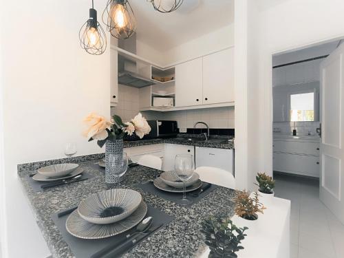 a kitchen with white cabinets and a table with plates at Sarah's Apartment - Playa Fañabe in Adeje