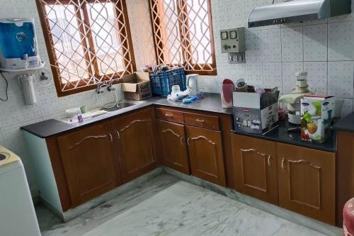 eine Küche mit Holzschränken, einem Waschbecken und Fenstern in der Unterkunft Ohm Shanthi Homestay in Puducherry