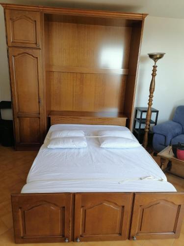 - un lit avec une tête de lit en bois et des draps blancs dans l'établissement Balcon sur la Méditerranée St Aygulf centre, 4 couchages, à Fréjus