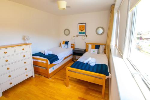 a bedroom with two beds and a dresser and a window at The Waves - Camber Sands - East Sussex in Camber
