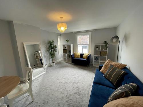 a living room with a blue couch and a table at Quintessential 2 Bedroom Apartment in the heart of Cookham in Maidenhead