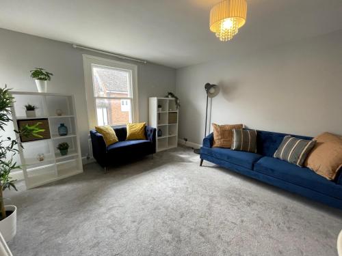 a living room with a blue couch and a chair at Quintessential 2 Bedroom Apartment in the heart of Cookham in Maidenhead