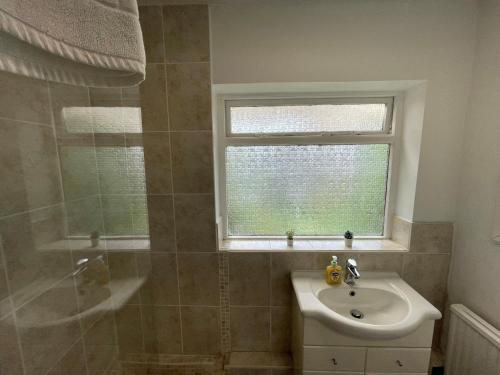 La salle de bains est pourvue d'un lavabo, d'une douche et d'une fenêtre. dans l'établissement Quintessential 2 Bedroom Apartment in the heart of Cookham, à Maidenhead