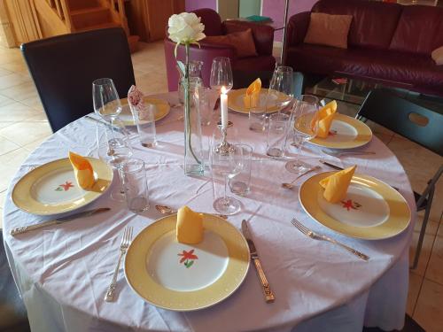 une table blanche avec des assiettes et des verres jaunes dans l'établissement Le Presbytère, à Saint-Romain