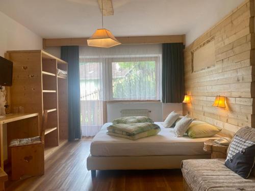 1 dormitorio con cama, sofá y ventana en Hotel Olympia, en Arabba