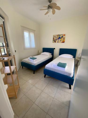 two beds in a room with a ceiling fan at The White Villa in Nydri