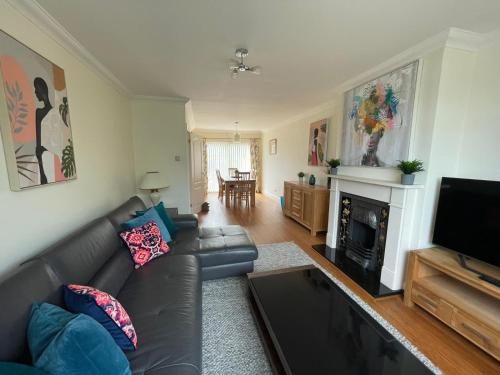 uma sala de estar com um sofá de couro e uma lareira em Addlestone Stylish Modern 3 bedroom house 6 em Addlestone