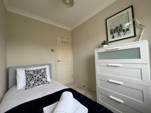 a bedroom with a dresser and a bed with a pillow at Addlestone Stylish Modern 3 bedroom house 6 in Addlestone