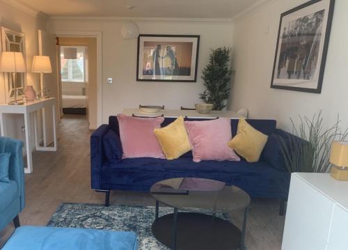 a living room with a blue couch with pink and yellow pillows at Flat 60, Longborn in Windsor