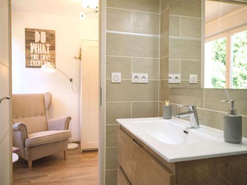 La salle de bains est pourvue d'un lavabo, d'une chaise et d'un miroir. dans l'établissement Villa Maurine - Piscine chauffée - Spa - Clim - Salle de Fitness, à Castelnau-de-Montmiral