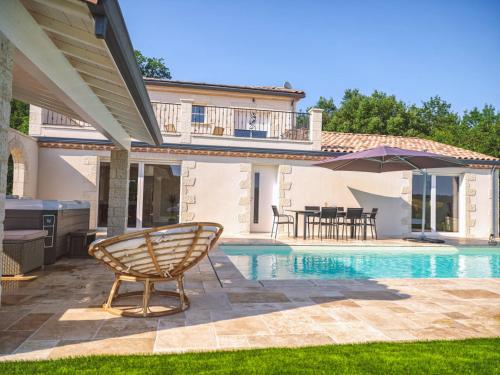 - une piscine avec une chaise et un parasol à côté d'une maison dans l'établissement Villa Maurine - Piscine chauffée - Spa - Clim - Salle de Fitness, à Castelnau-de-Montmiral