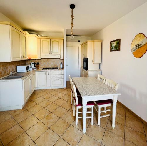 eine Küche mit weißen Schränken sowie einem Tisch und Stühlen in der Unterkunft Casa Anselmo in Loano