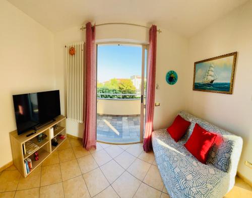 ein Wohnzimmer mit einem Sofa, einem TV und einem Fenster in der Unterkunft Casa Anselmo in Loano