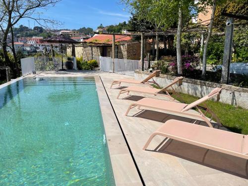 a row of lounge chairs next to a swimming pool at SantiagoFamilyHouse - Casa Velha - Cottage in Sever do Vouga
