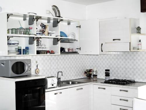 cocina blanca con fregadero y microondas en Charming 2-Bed House in Albaro for every Traveler, 