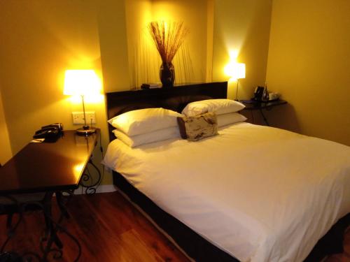 a bedroom with a large white bed with two lamps at Protea Hotel by Marriott Bloemfontein in Bloemfontein