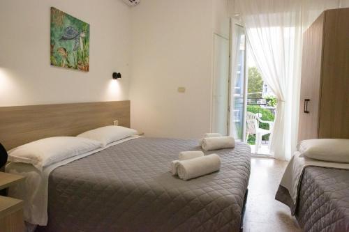 a hotel room with two beds and a window at Villa Ella by Interlux in Rimini