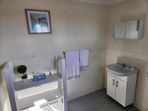 uma casa de banho com lavatório, WC e toalhas em Cozy Cabin Country Cottage em Skeerpoort