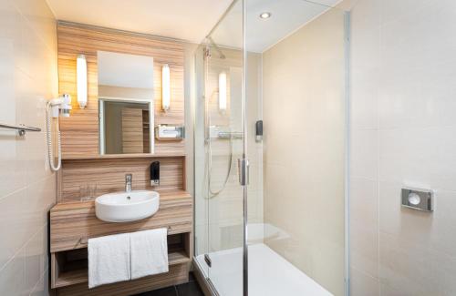 a bathroom with a sink and a glass shower at Leonardo Boutique Hotel Linz City Center in Linz