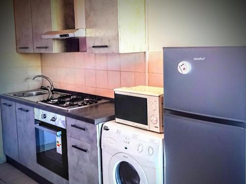 een keuken met een wasmachine en een magnetron bij Casa freogan in Castelsardo