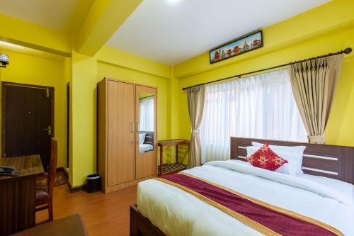 a bedroom with a bed and a desk and a window at Deepjyoti Inn in Pashupatināth