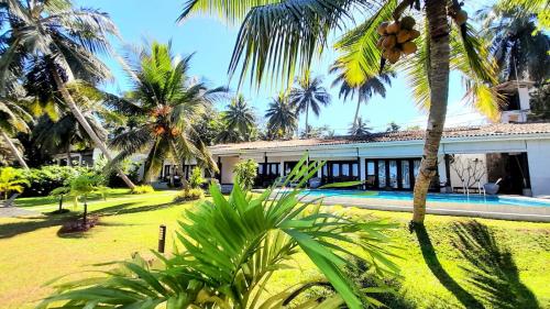 une villa avec une piscine et des palmiers dans l'établissement Chaleni Villa, à Bentota