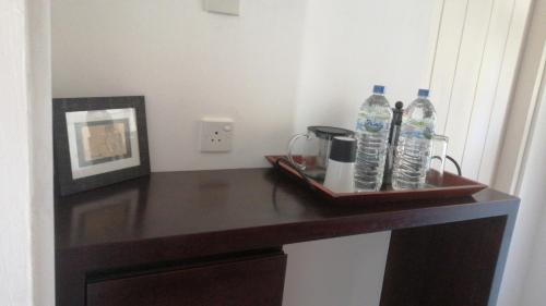 - une table avec un plateau de bouteilles d'eau et une photo dans l'établissement Chaleni Villa, à Bentota