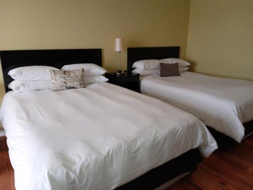 two beds in a hotel room with white sheets and pillows at Protea Hotel by Marriott Bloemfontein in Bloemfontein
