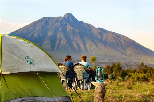 a group of people sitting in chairs in front of a mountain at Under Volcanoes View Guest House in Nyarugina