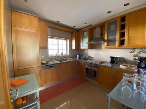 a kitchen with wooden cabinets and a stove top oven at Casa M Falésia in Albufeira