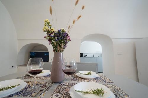Trullo Lis con Piscina Privata في سان ميكيلي سالنتينو: طاولة مع كأسين من النبيذ و إناء من الزهور