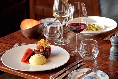 a table with plates of food and glasses of wine at Ellenborough Park in Cheltenham