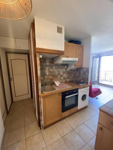 une petite cuisine avec un évier et une cuisinière dans l'établissement Appartement T3 avec terrasse donnant sur la mer sur Saint Pierre la Mer, à Saint Pierre La Mer