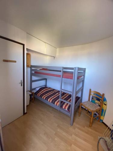 2 lits superposés dans une chambre avec une chaise et une porte dans l'établissement Appartement T3 avec terrasse donnant sur la mer sur Saint Pierre la Mer, à Saint Pierre La Mer