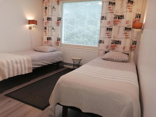 two beds in a room with a window at Majoituspalvelu Nurmi Apartment Peipontie 3 A Saunallinen Huoneisto in Raahe