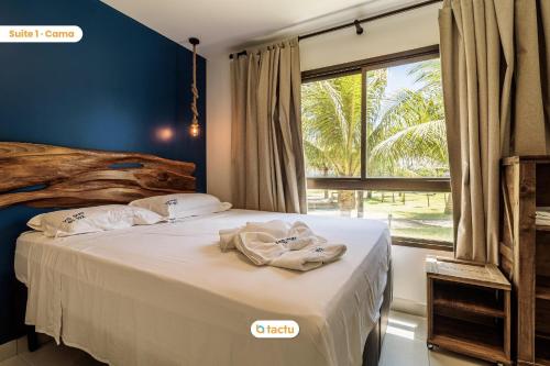 um quarto com uma cama com lençóis brancos e uma janela em Lindo térreo espaçoso no VG Sun Cumbuco por Tactu em Cumbuco