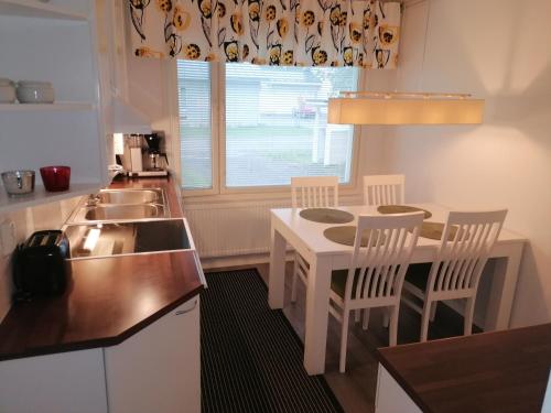 a kitchen with a table and chairs and a sink at Majoituspalvelu Nurmi Apartment Peipontie 3 A Saunallinen Huoneisto in Raahe